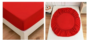 Detail of red fitted sheet with elastic band showing snug corner fit and circular design