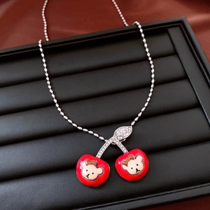 Detailed macro view of red enamel cherry pendant with bear motif and zircon inlay