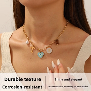Détail du collier à chaîne dorée avec pendentifs œil, perle et lettre sur le mannequin