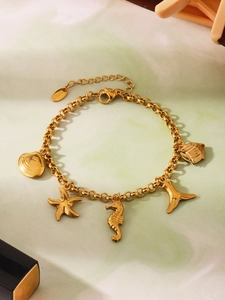 Détail du bracelet en acier inoxydable doré avec breloques hippocampe et étoile de mer