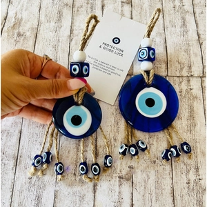 Detailed view of blue glass Evil Eye charms with jute rope on a light wood background