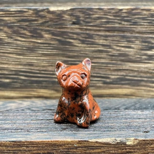 Detailed view of hand-carved red and black spotted gemstone French Bulldog on wood surface