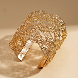 Detailed macro view of gold mesh woven cuff bracelet with intricate metal textures