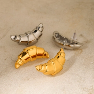 Macro shot of gold and silver croissant dome earrings on a marble surface