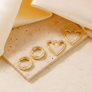 Elegant gold-plated heart and circle hoop earrings set displayed on silk and stone