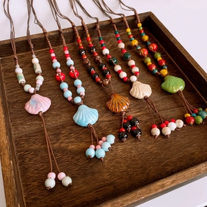 Detail of colorful ceramic shell pendants with bohemian beaded tassels on a wooden tray