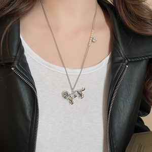 Detail of silver puppy pendant necklace with zircon bow and pearl accent on chain