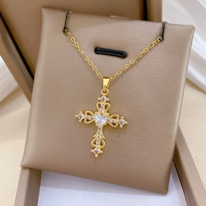 Macro shot of gold cross necklace with hollow heart and crystals in jewelry box