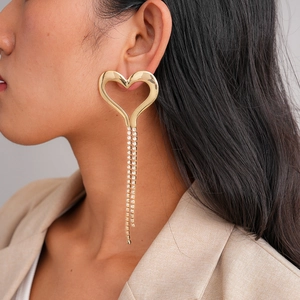 Detail view of large golden heart-shaped fringe earrings with tassels on female model