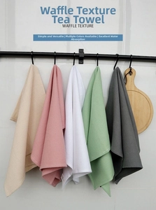 Detailed view of waffle texture tea towels in multiple colors hanging on a kitchen rack
