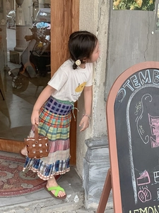 Detail of a brown woven mini bucket bag paired with a colorful patchwork cake skirt