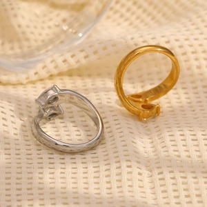 Close-up of gold and silver teardrop zircon rings on a soft woven fabric background