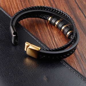 Detail of multi-layer black braided leather bracelet with gold textured metal rings