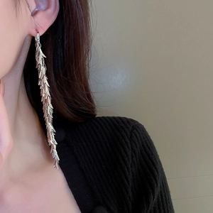 Close-up of silver leaf tassel earrings with layered metal fringe design on a model