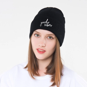 Detailed close-up of white good vibes embroidery on black knitted beanie cuff