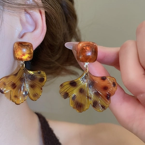 Détail macro de boucles d'oreilles ginkgo en résine ambre montrant la texture naturelle