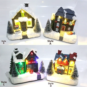Close-up of lit miniature Christmas house with snow texture and internal LED lights