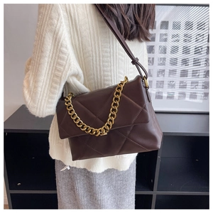 Detail van donkerbruine gewatteerde crossbodytas met gouden ketting en driehoekpatroon