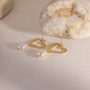 Detailed shot of gold heart earrings with freshwater pearls on a white crystal stone