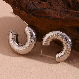 Close-up of silver hammered texture hoop earrings on a minimalist natural wood background