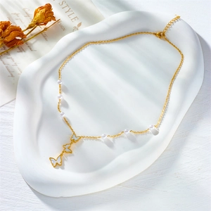 Elegante collana dorata con ciondoli a farfalla e perle su un vassoio decorativo