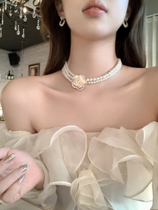Detailed close-up of a three-layer pearl choker with a yellow flower pendant on a model