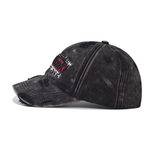 Detail of washed black vintage baseball cap with red York embroidery and distressed holes