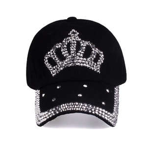 Close-up of sparkling silver rhinestone crown and studded brim on black cotton baseball cap