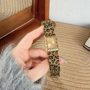 Detailed shot of retro gold rectangular watch with leopard print mesh strap and roman numerals