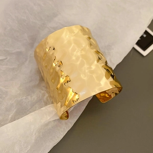 Macro detail of golden hammered texture on wide irregular metallic cuff bracelet