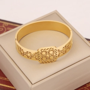 Detail of a hollowed golden sunflower bracelet placed on a cream leather jewelry box