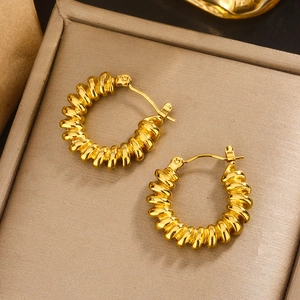 Detailed view of large gold U-shaped hoop earrings with retro spiral texture in a jewelry box