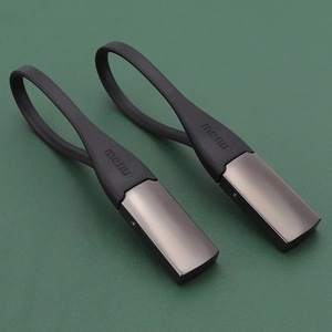 Minimalist black metal and rubber car keychain set displayed on dark leather surface