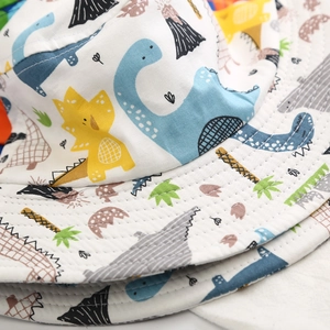 Close-up detail of a cotton children's bucket hat with colorful cartoon dinosaur pattern.