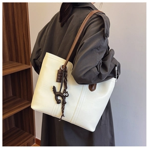 Detail of off-white PU leather tote bag with brown straps and cute cat charms