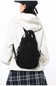 Detailed back view of a black lightweight nylon sports backpack on a model's back