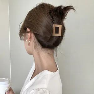 Close-up of a matte brown square hair claw clip styled on a model in a casual setting