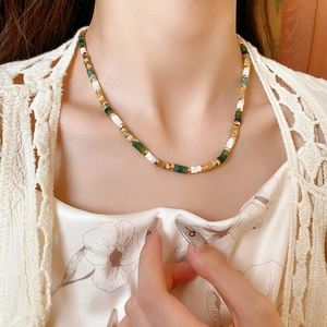 Detail view of multi-color beaded necklace with stones, pearls and wooden discs on a model