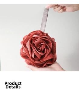 Detail of deep red rose shaped mesh bath sponge held in hand with grey hanging cord