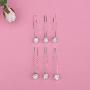 Detail of six silver U-shaped hair pins with sparkling rhinestone balls on pink backdrop