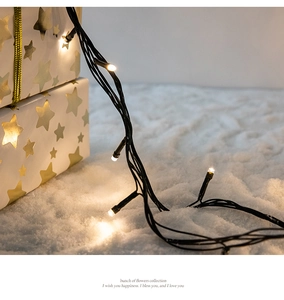 Detail of warm white LED fairy lights wrapped around a white gift box on a snowy background