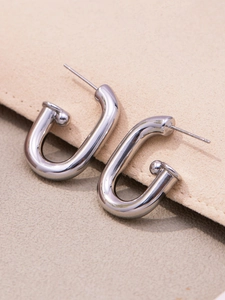 Gros plan de boucles d'oreilles clous en métal poli argenté en forme de U sur daim