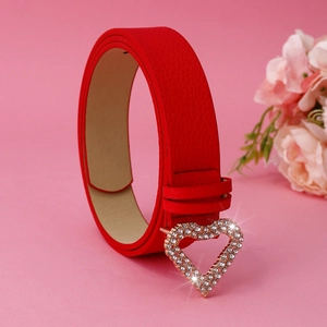 Detail of red leather belt featuring a gold heart-shaped buckle with sparkling rhinestones