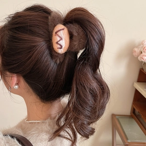 Detailed close-up of brown flocked bread-shaped hair claw clip on curly hair