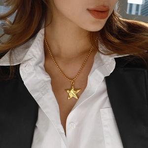 Star pendant necklace in gold stainless steel with ball chain shown on a model
