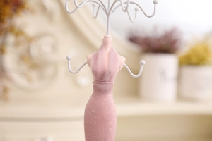 Detailed view of pink velvet mannequin jewelry stand with white metal hooks for storage