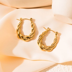 Detail showing high-polish gold croissant hoop earrings on silk fabric backdrop