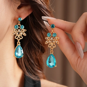 Detailed shot of vintage gold earrings featuring large blue teardrop rhinestones