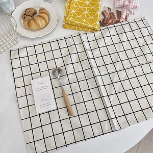 Close-up of black and white checkered linen placemat with wooden spoon and plate