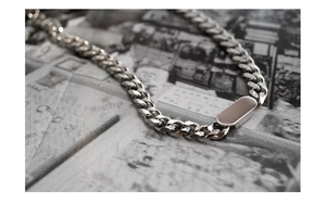 Close-up of silver titanium steel Cuban link chain necklace with polished rectangle clasp